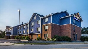 A multi-story hotel with a blue and brick exterior, a prominent sign, and a well-maintained front yard. - Baymont By Wyndham Bloomington Msp Airport (Richfield)