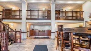 A hotel lobby with a reception desk, a staircase, and a bar area. - Baymont By Wyndham Bloomington Msp Airport (Richfield)