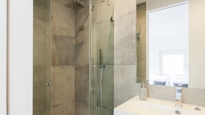 Une salle de bain moderne avec une douche à parois de verre, un lavabo blanc et un grand miroir.