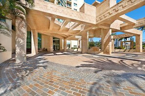 A spacious courtyard with a patterned brick floor, large columns, and a modern architectural design.