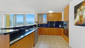 A modern kitchen with wooden cabinets, a black countertop, and a view of the city.