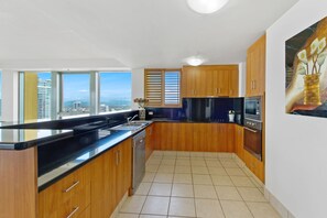 Une cuisine moderne avec des meubles en bois, un plan de travail noir et une vue sur la ville.