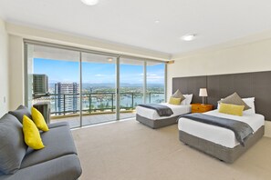 Enjoy a panoramic view of the city and water from the balcony, featuring a sofa and two single beds.