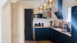 Una cucina moderna con mobili in legno, forno a microonde integrato e illuminazione a sospensione.