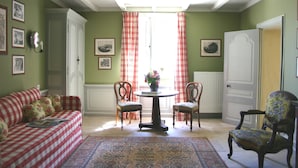 Una habitación con un sofá a cuadros, dos sillones, una mesa con un jarrón y una alfombra estampada.