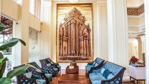 A lobby with a large wooden artwork, a reception desk, and seating area with blue upholstered chairs. - Tran Vien Dong Hotel (Nha Trang)
