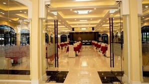 A spacious banquet hall with a polished floor, rows of tables with red tablecloths, and a central stage. - Tran Vien Dong Hotel (Nha Trang)