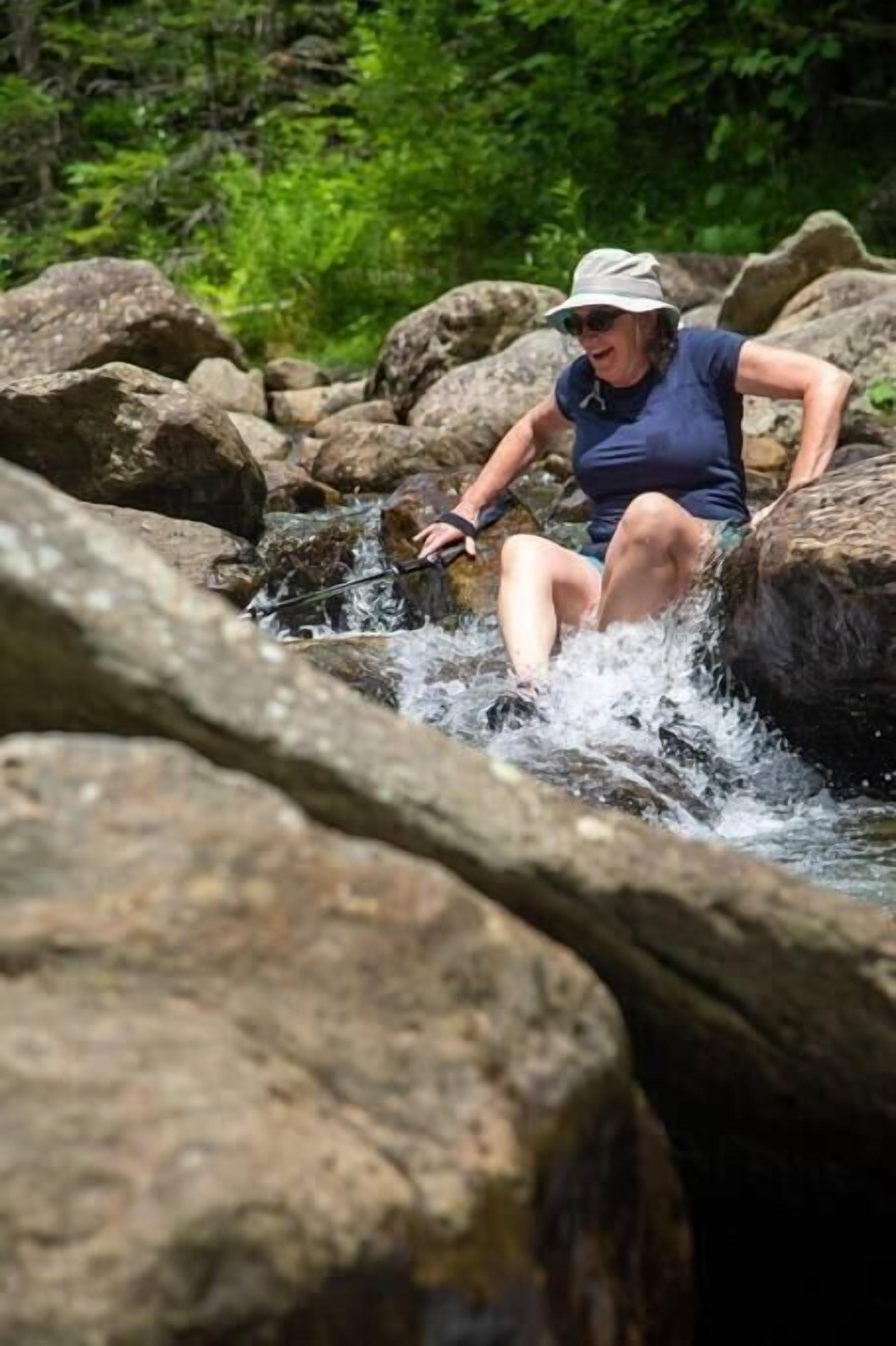 A person navigating a rocky stream in a natural setting.