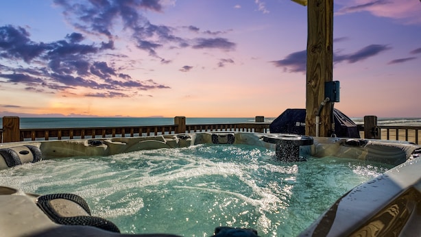 A hot tub with a wooden deck overlooking the ocean at sunset. - Beachfront | Hot Tub, Bar & Stunning Views (Bolivar Peninsula)