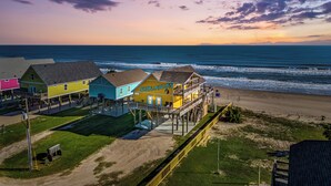 A coastal hotel with multiple colorful buildings, a boardwalk, and a view of the ocean. - Beachfront | Hot Tub, Bar & Stunning Views (Bolivar Peninsula)