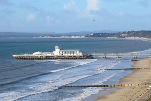 A coastal scene with a pier extending into the sea, a beach, and a distant hill range. - Stunning one Bedroom Apartment in Bournemouth (Bournemouth)