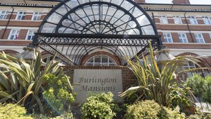 L’entrée de Burlington Mansions se distingue par un grand auvent en verre en forme d’arche et une enseigne.