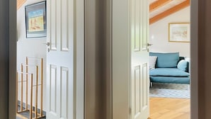 Ein Zimmer mit Holzbalkendecke, einem blauen Sofa und einem gerahmten Bild an der Wand.