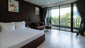 A modern hotel room with a large bed, a sofa, a small table, and a balcony with a view. - Tuan Ninh Hotel 2  (Ho Chi Minh City)