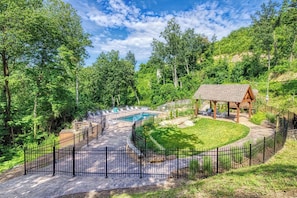 A pool area with a wooden deck, lounge chairs, and a gazebo.