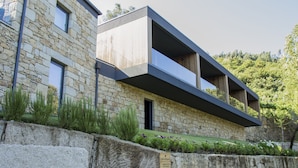 A modern building with stone walls, a balcony, and a sign indicating a garden area.