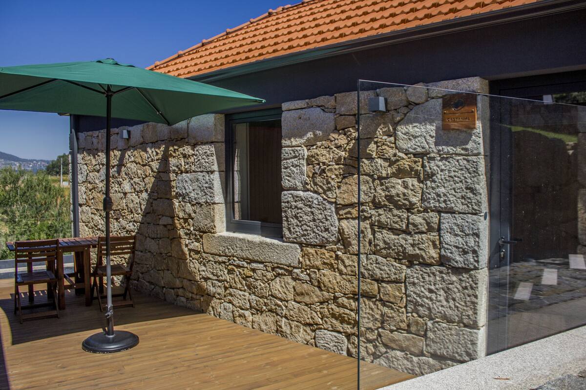 A stone building with a wooden deck, a glass door, and a green umbrella.