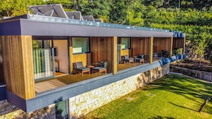 A modern house with a covered patio, large windows, and a stone foundation.