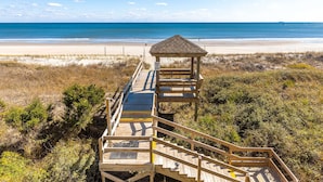 A wooden boardwalk leading to a beach with a gazebo.