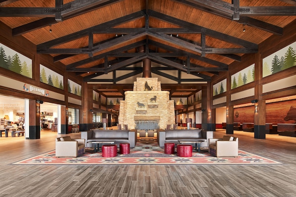 A spacious lobby with a high wooden ceiling, a stone fireplace, and leather seating areas. - Great Wolf Lodge Manteca (Manteca)