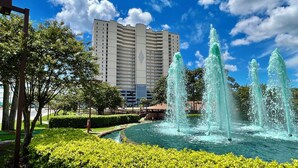 Un hotel con un edificio amplio, una fuente y jardines bien cuidados.
