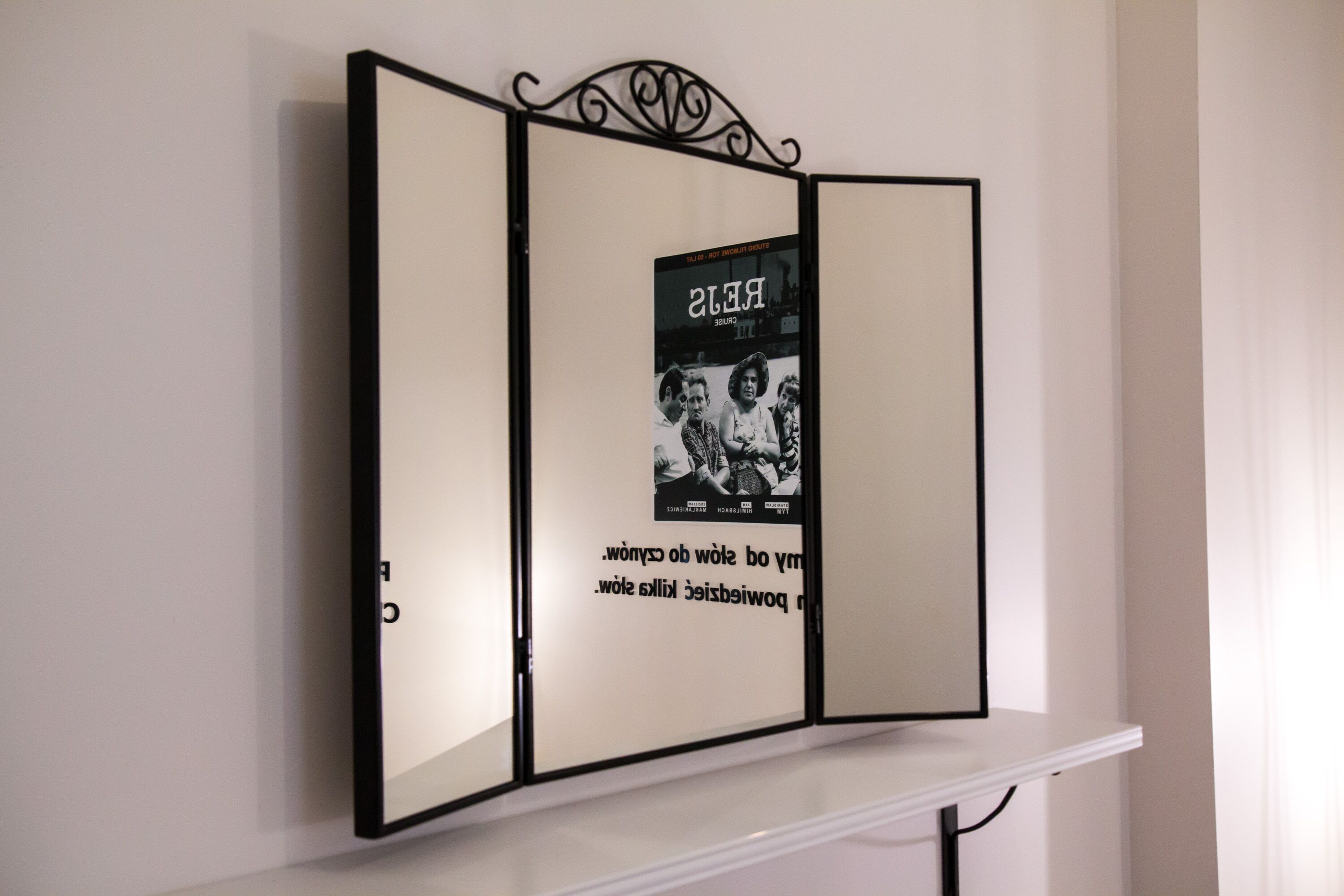 A wall-mounted, three-panel display with a central black-and-white photograph and text.