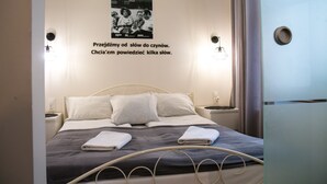 Un letto rifatto con cuscini e coperta, un quadro appeso al muro e un comodino con una lampada.