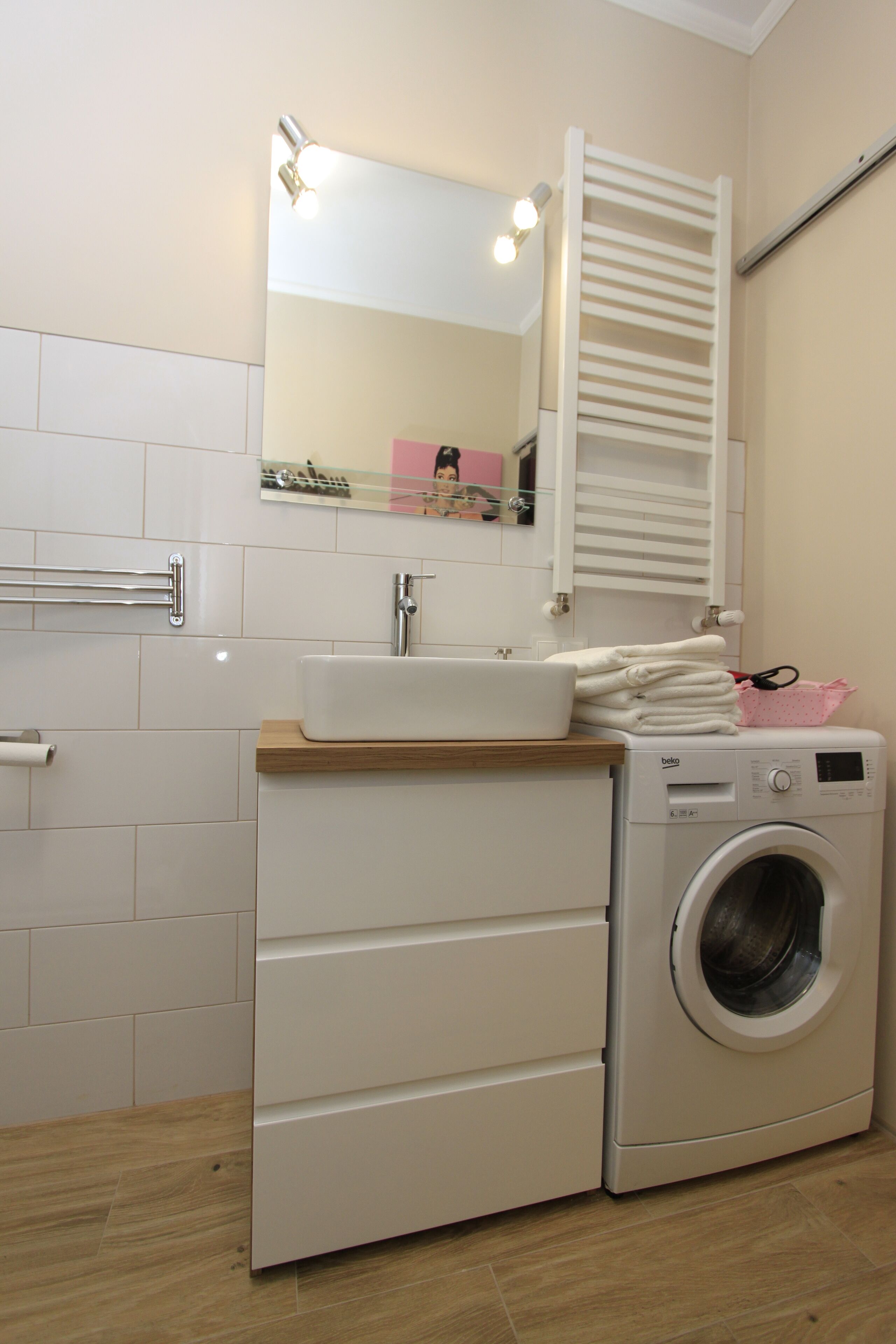 Un baño pequeño con lavadora, lavamanos y espejo.