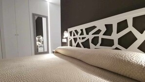 Ein Schlafzimmer mit einem Bett, einem weißen Kopfende und einer Tür zu einem anderen Raum.