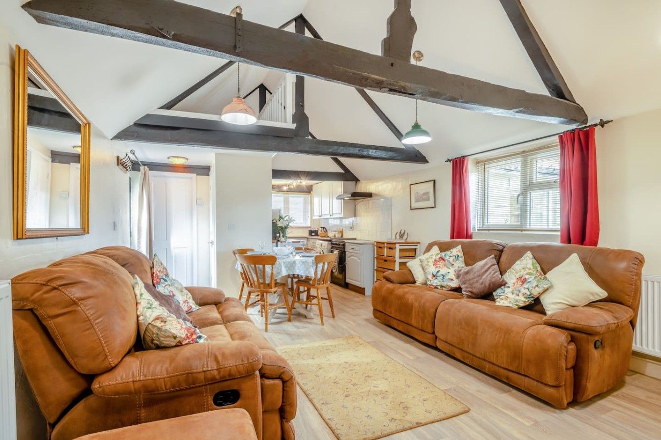 A spacious living room with leather sofas, a dining area, and a kitchen in the background.