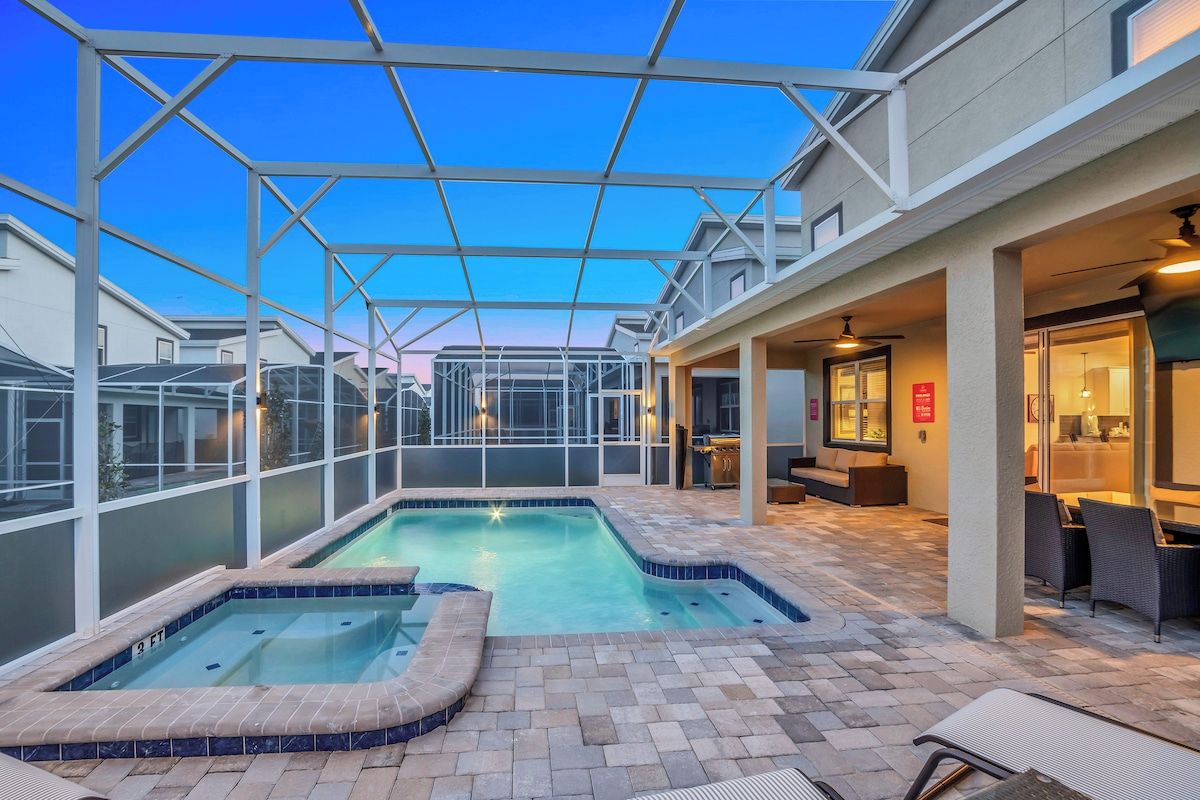 A pool area with a glass enclosure, lounge chairs, and a bar area.