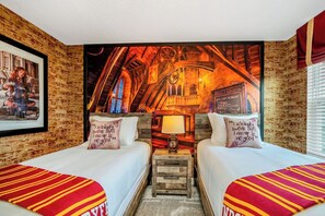 Et værelse med to senge, et muralmaleri og et lille bord med en lampe.