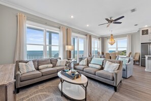 A spacious living room with a large window, a ceiling fan, and a dining area with a view.