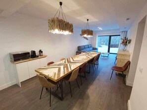 Une cuisine moderne avec une longue table en bois, un four encastré et une machine à café.
