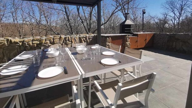 An outdoor patio with a table set for dining, stone walls, and a chimney.