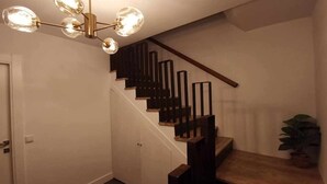 A staircase with a modern design, featuring a wooden handrail and black railings.