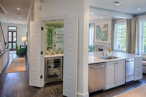 A modern kitchen with white cabinetry, a built-in wine cooler, and a large window providing natural light.