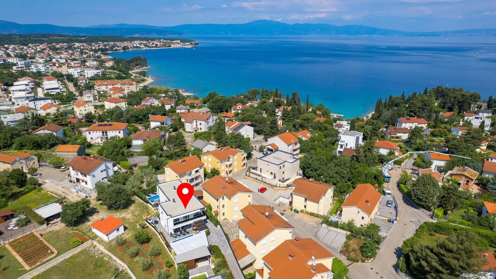 An aerial view of a coastal residential area with houses, a marina, and a large body of water.