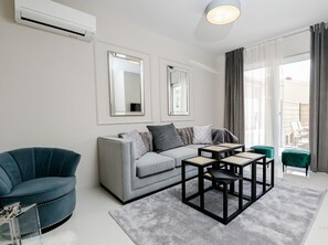 A modern living room with a grey sofa, a blue armchair, and a coffee table with four square side tables. - Stylish Villa Metra Maris1 with a sea view and a pool on Krk (Malinska)