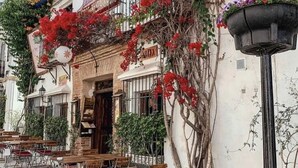 A restaurant with outdoor seating, a balcony with red flowers, and a street lamp. - B&B Villa Maria Guest Rooms - San Roque Golf - Sotogrande (San Roque)
