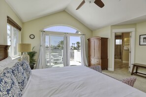 Ein Schlafzimmer mit einem großen Bett, einem Deckenventilator, einem Holzschrank und Blick ins Freie.