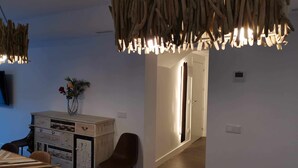 A modern dining area with a wooden table and chairs, a vase with flowers, and a unique hanging light fixture.
