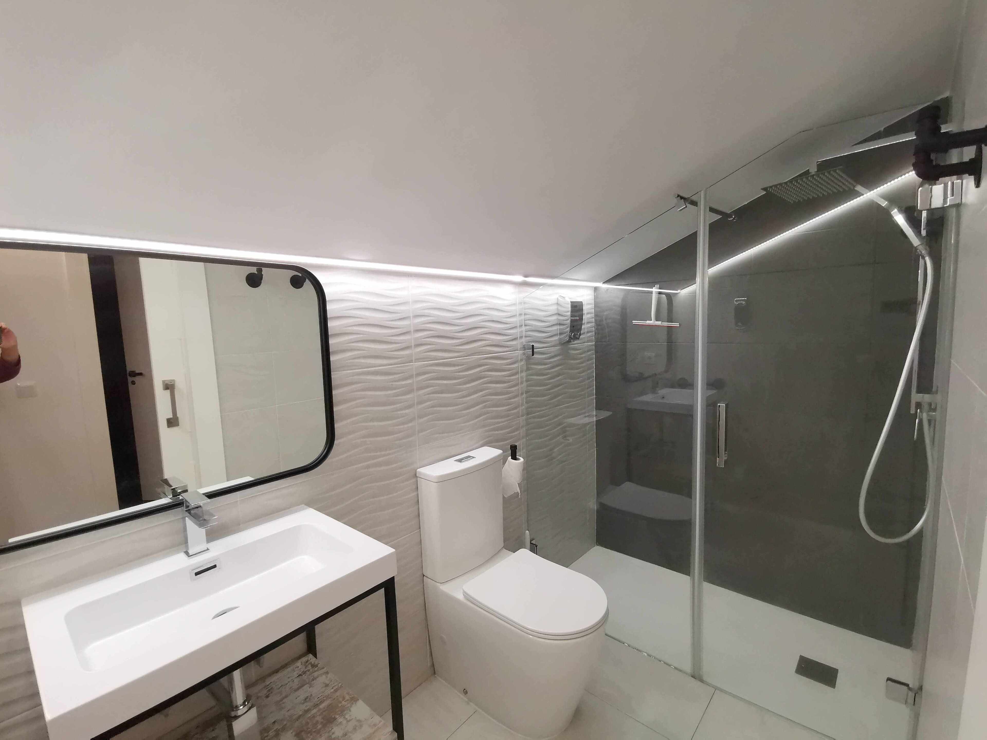 A modern bathroom with a white sink, toilet, and glass-enclosed shower.