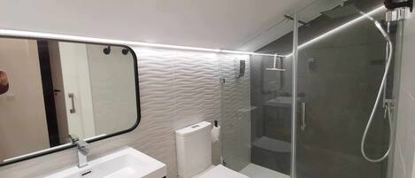 A modern bathroom with a white sink, toilet, and glass-enclosed shower.