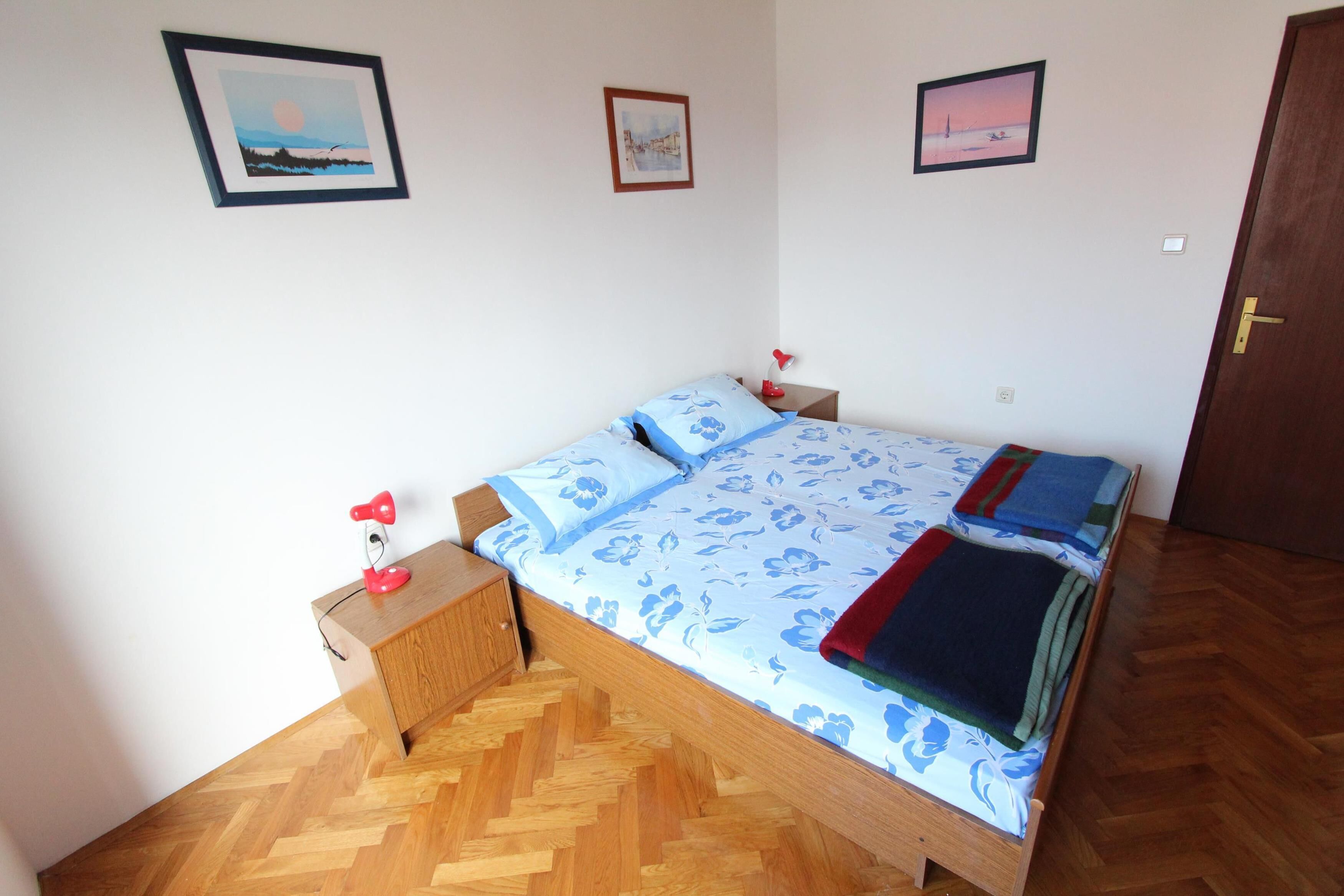 A bedroom with a wooden bed, two bedside tables, and three framed pictures on the wall.