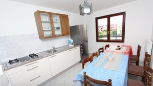 Una cocina moderna con armarios blancos, un refrigerador de acero inoxidable y un comedor con mantel azul.