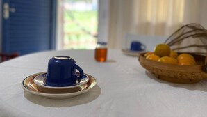 A table with a blue teapot, a bottle of tea, and a basket of oranges.