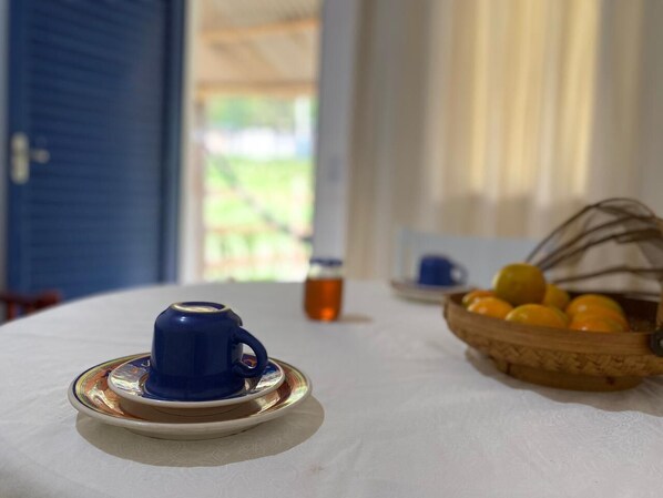A table with a blue teapot, a bottle of tea, and a basket of oranges.