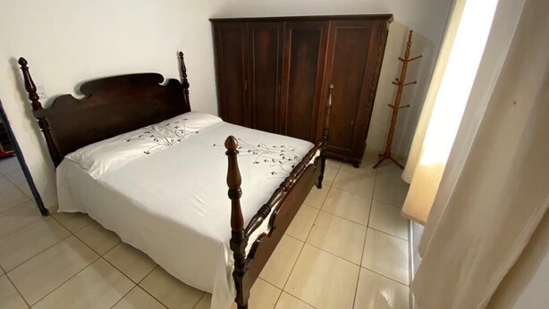 A bedroom with a wooden bed, a wardrobe, and a coat rack.