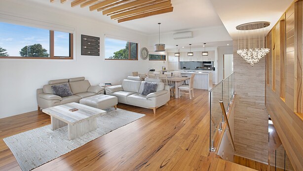 A modern living room with a sofa, coffee table, and a dining area with chairs.